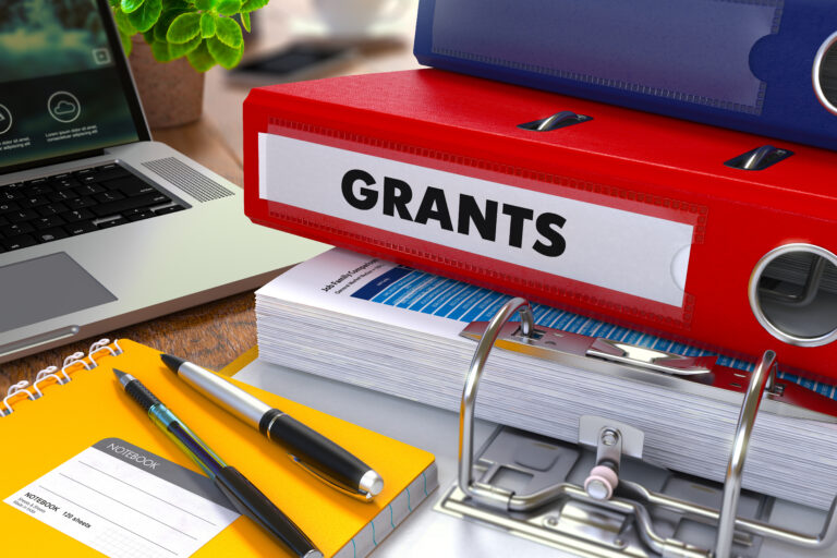 Stack of folders with red folder named Grants